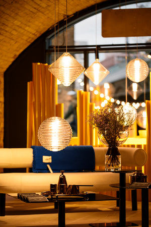 A yellow-coloured showroom with several lamps and sofas scattered around the room