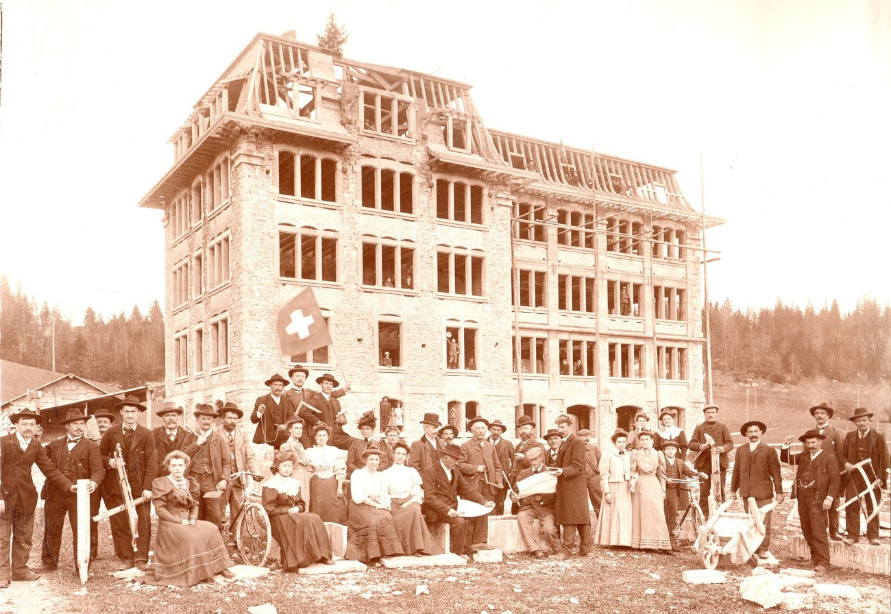 A brown-toned antique photo of the watchmaking school that Dufour attended, with a group of people posing for photographs outside it